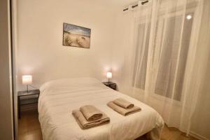 ein weißes Schlafzimmer mit einem Bett mit Handtüchern darauf in der Unterkunft Ideal family flat in st-ouen in Saint-Ouen