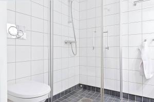 La salle de bains est pourvue de toilettes et d'une douche en verre. dans l'établissement Sørenga MUNCH ved kanalen - egen terrasse uteplass, à Oslo