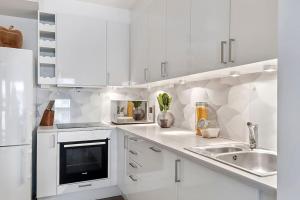 a white kitchen with white cabinets and a sink at Oceanfront Apartment - Oslo Central - Private Patio in Oslo