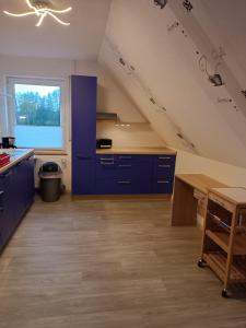 a kitchen with blue cabinets and a large window at Gästehaus Atrico Schleuse Wg 1 in Surwold