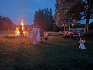 a group of people standing around a bonfire at night at Agroturystyka Sòjkowy Zakątek in Dzierżążno Małe