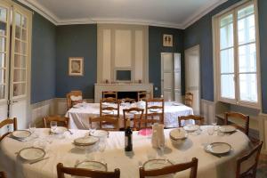 een grote eetkamer met tafels, stoelen en ramen bij Le Logis de Louis in Saint-Savin