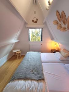 sypialnia na poddaszu z 2 łóżkami i oknem w obiekcie Chalet Het Bosnestje Durbuy w mieście Durbuy