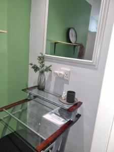 a glass table with a mirror and a clock on a wall at Eland Place Self Catering Guest House in Beacon Bay