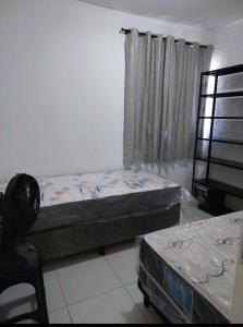 two beds in a room with a window at APARTAMENTO 2 QUARTOS MOBILIADO - GARANHUNS - PE in Garanhuns