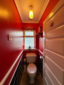a red bathroom with a toilet and a window at Quebec House - Free Parking and Wifi, 'Comfortable Spacious House Near to Town Centre in Swindon