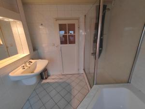 y baño blanco con lavabo y ducha. en Gemütliches Haus mit schönem Garten, en Viena