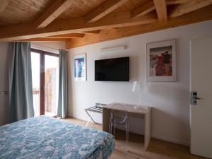um quarto com uma cama, uma secretária e uma televisão em Foresteria Lago di Como em Menaggio