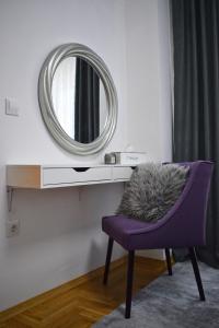 a mirror and a purple chair in a room at BorLu apartman in Đakovo