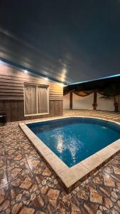 a swimming pool in a house with a stone floor at Ark Chalet in Hail