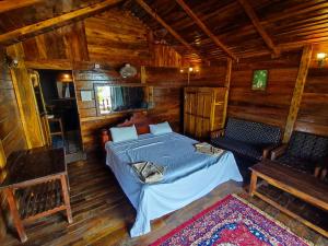a bedroom with a bed in a wooden cabin at Sea Front Cottage Little Khola in Cola