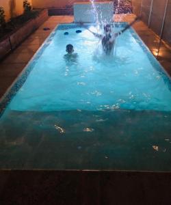 two people in a swimming pool with a fountain at Hermosa y Amplia Casa Familiar en Alta Gracia in Alta Gracia