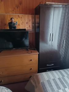 um homem tirando uma foto de uma TV em um quarto em Residencial familiar em Puerto Montt