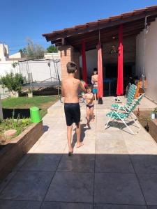 Ein Mann und zwei Kinder, die auf einer Terrasse spazieren in der Unterkunft Hermosa y Amplia Casa Familiar en Alta Gracia in Alta Gracia