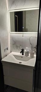 a white bathroom sink with a large mirror and a sink at The Velvet in Chişinău