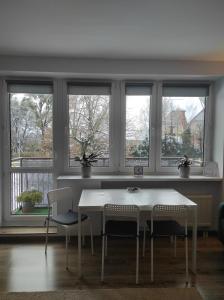 una mesa blanca y sillas en una habitación con ventanas en Apartament Piłsudskiego en Szczytno