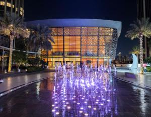 杜拜的住宿－The Address Residences Dubai Opera , Full Burj Khalifa View , Luxurious 2BR，夜间在建筑物前的喷泉