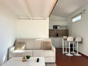 a living room with a couch and a kitchen at Appartement à 100M de la plage - Terrasse & Parking Privé in Le Barcarès