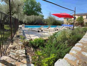 a red umbrella sitting next to a swimming pool at Maison de vacances à louer dans le Gard Provençal, semaine de 7 jours minimum, samedi au samedi, 10 personnes, Le Mas du Colombier in Saint-Michel-dʼEuzet