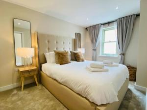 um quarto com uma grande cama branca e um grande espelho. em Luxurious Beach House Chesil Beach. Sleeps 6 em Castletown