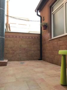 un patio con una pared de ladrillo y un taburete verde en Casa bien Situada Chez Mahinna en Cehegín