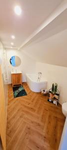 a bathroom with a white tub and a wooden floor at Apartamenty Diamond na Sportowej in Tylicz