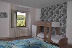 ein Schlafzimmer mit einem Etagenbett und einem Fenster in der Unterkunft Le Gîte des Petits Cailloux 