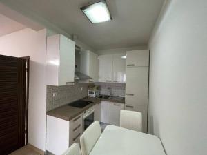 uma cozinha com armários brancos e uma mesa e cadeiras em Central City Apartment em Pristina
