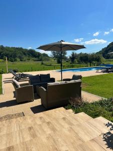 un patio con sofás y una sombrilla junto a la piscina en Ruralna kuca 'Villa Zagorka' za odmor sa bazenom i bočalištem, en Donja Pačetina