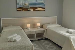 twee bedden in een kamer met twee lampen en handdoeken bij Aleph Guest House relax a due passi dal mare in Fertilia