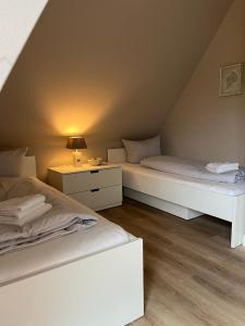 タツィングにあるReetdach-Landhaus Mini Haubargのベッドルーム1室(ベッド2台、ランプ付きテーブル付)