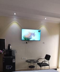 a flat screen tv on a wall with two chairs and a table at B&S Studio apartment, Voi Town in Voi