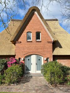 una casa de ladrillo con techo de paja en Reetdach-Landhaus Mini Haubarg en Tating