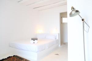 a white bedroom with a bed and a lamp at Paradise Estate Community in Paraga