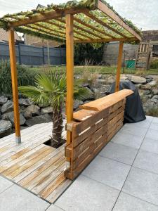 eine Holzbank unter einer Pergola auf einer Terrasse in der Unterkunft Chambre privée à 10 min du circuit in Parigné-lʼÉvêque