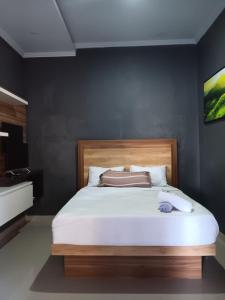 een slaapkamer met een wit bed en een houten hoofdeinde bij BALI MOUNT VIEW META PANDAWA in Jembrana