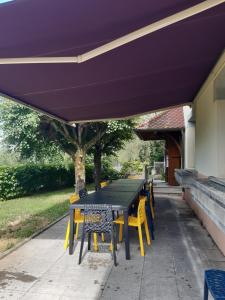 einem Picknicktisch mit gelben Stühlen und einer lila Markise in der Unterkunft Le Gîte des Petits Cailloux 