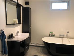 een badkamer met een bad, een wastafel en een spiegel bij Near commuter train to Stockholm in Södertälje
