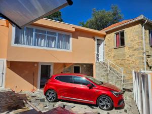 Ein rotes Auto parkte vor einem Haus in der Unterkunft Casasoutelo in Carrazedo