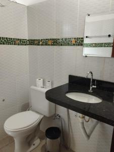 a bathroom with a white toilet and a sink at Pousada Luz do Sol in Sao Jorge