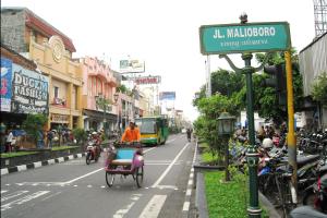 a person riding a bike down a city street at Hotel Pules in Yogyakarta
