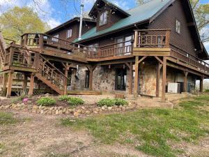 une grande maison en bois avec une grande terrasse dans l'établissement Buffalo River Lodge St Joe AR, à Maumee