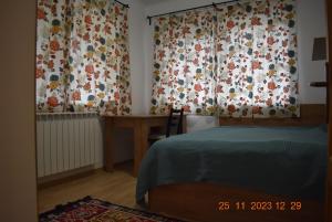 a bedroom with a bed and a desk and curtains at Capra cu trei iezi in Sinaia