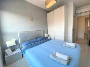 La HoradadaにあるAppartement Mil palmerasのベッドルーム1室(大型ブルーベッド1台、タオル2枚付)