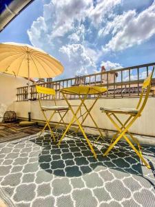 2 tables jaunes et un parasol sur une terrasse dans l'établissement Hypercentre terrasse clim, à Aix-en-Provence