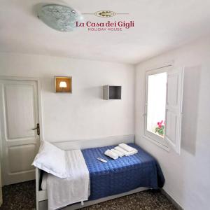 a bedroom with a bed with blue sheets and a window at La Casa dei Gigli in Lecce
