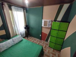 a bedroom with a green bed and a window at Palm house Arenal in Fortuna