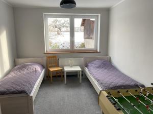 Zimmer mit 2 Betten, einem Tisch und einem Fenster in der Unterkunft Dom w Kotlinie in Długopole-Zdrój