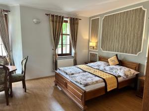 a bedroom with a bed and a table and windows at Pension Robin in Jáchymov