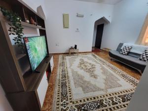 sala de estar con TV y sofá en Relaxation Oasis, en Al Ḩamrāʼ